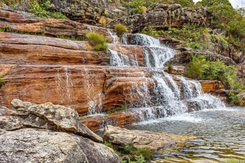 Small waterfall with clear water running over the rocks and ending in a small lake in the Biribiri environmental reserve in Diamantina