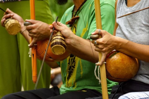 Musicians playing an Afro Brazilian percussion musical instrument called a berimbau during a capoeira performance in the streets of Brazil