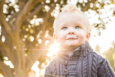 Smiling blonde baby boy outdoors at the park