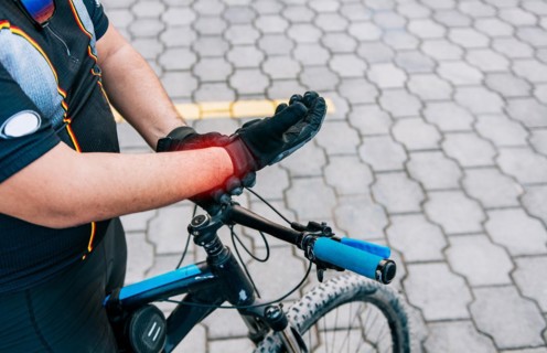 Cyclist man with hand pain outdoors. Close up of cyclist with arthritis outdoors