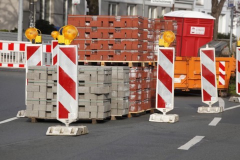 Stacked red building blocks with barrier beacons on a construction site for a cycle path