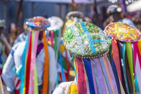 Men dressed in colorful clothes and hats attending a popular religious festival in Minas Gerais