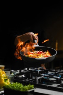 Flambering wok ingredients in a frying pan