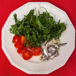 Italian dish from Italian cuisine served on a plate Starter Primo Piatto Marinated anchovies Alici marinate with fresh ruccola Ruccola salad and halved small tomatoes
