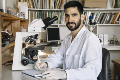 Young scientist in front of microscope