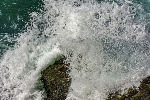 Sea water splashing in the air with the wave crashing against the rocks