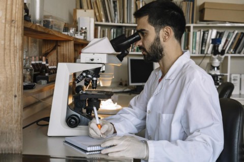 Male scientist looking under microscope