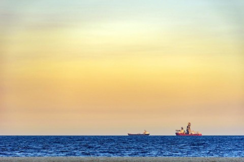 Ships on the horizon during tropical sunset at Copacabana beach in Rio de Janeiro