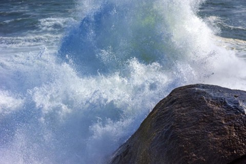 Stormy wave crashing against the rocks with sea water splashing in the air