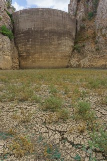 This striking photograph depicts a reservoir dam during a severe drought. The reservoir