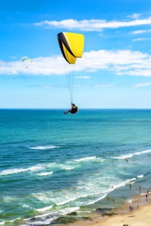 Paraglider flight over the beach in the city of Torres in Rio Grande do Sul with the sea and horizon in the background