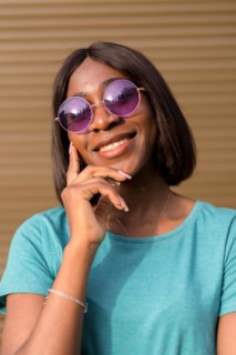 Capturing the Essence of Summer: A Portrait of a Young African American Tourist in a Green T-Shirt and Shades Against a Brown Wall
