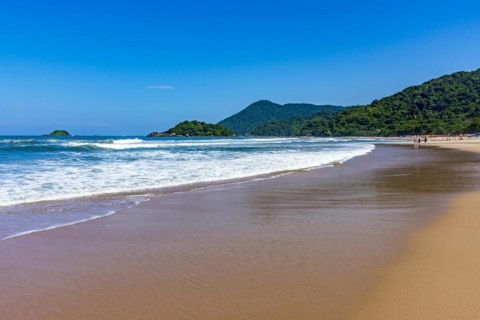 Paradise beach surrounded by rainforest and hills on a sunny day in Bertioga on the coast of Sao Paulo