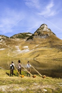 The Austrian alphorn trio Klangholz plays the alphorn at the Augstsee on Mount Loser
