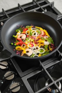 Frying fresh vegetables and shrimps in a frying pan