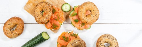 Bagel sandwich for breakfast topped with salmon fish from above on a wooden board Panorama in Stuttgart