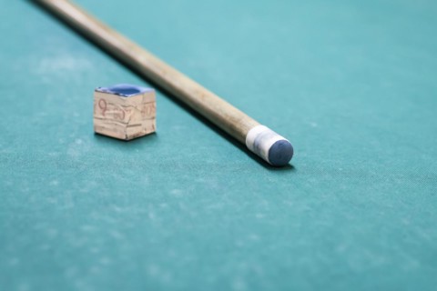 A cue stick and a chalk on a pool table