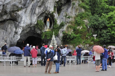 Pilgrims praying in front of the grotto at the Sanctuary of Our Lady of Lourdes