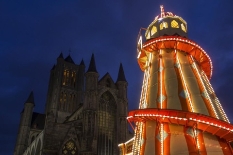 Illuminated helter skelter at evening Christmas market and the Saint Nicholas church