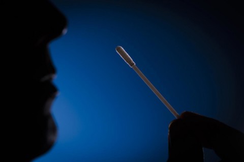 A man holds cotton swabs of a Sars-COV-2 Rapid Antigen Test to his nose. Berlin