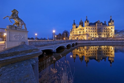 Illuminated Schwerin Castle with the castle bridge to the castle island in the evening