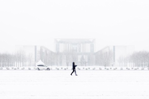 A person is silhouetted in front of the Chancellery in the driving snow in Berlin