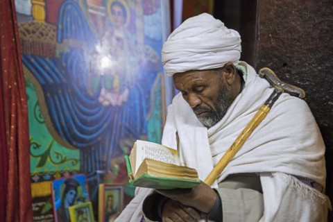 Priest reading the bible at Biete Medhane Alem