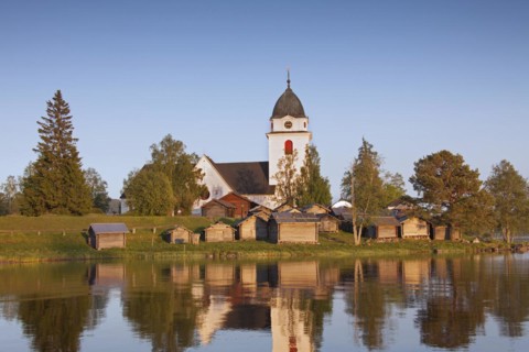 The picturesque old Raettvik Church surrounded by horse stables along Lake Siljan