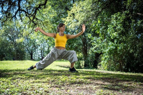 Profile of a woman practicing tai chi surrounded by trees. Chinese martial arts