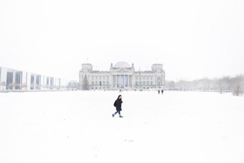 A person stands in front of the Bundestag in the driving snow in Berlin