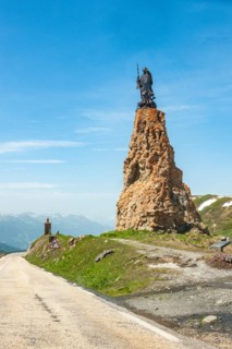 Satue of monk of Cistercian Order Bernard de Clairvaux Bernard of Clairvaux on rock pillar on top of pass of Alpine pass road Little Saint Bernard in Graian Alps