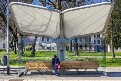 Rain and sun protection over park bench and man with knitted cap