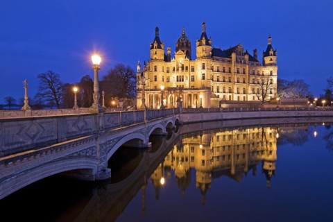Illuminated Schwerin Castle with the castle bridge to the castle island in the evening