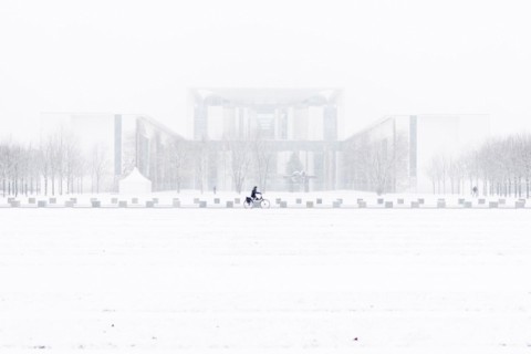 A person is silhouetted in front of the Chancellery in the driving snow in Berlin