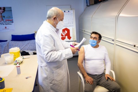 A pharmacist goes through a medical history sheet with a man in front of a Covid-19 vaccination in Duesseldorf