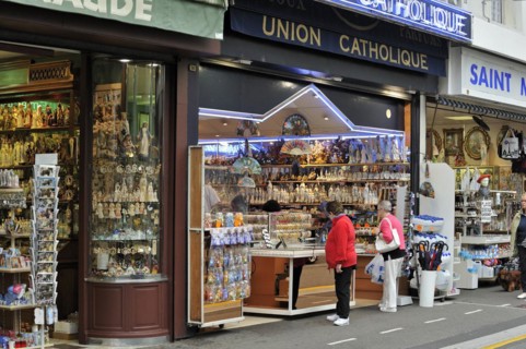 People buying religious souvenirs in souvenir shop near the Sanctuary of Our Lady of Lourdes