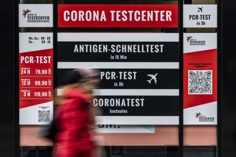 A person stands out in front of large-scale advertising for a Corona test centre in Berlin