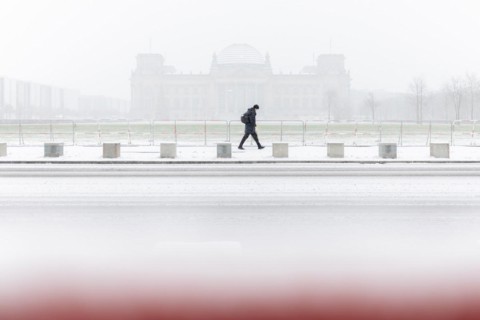 A person stands in front of the Bundestag in the driving snow in Berlin