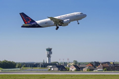 Control tower of Brussels Airport and the village Steenokkerzeel behind runway of Brussels Airlines while airplane is taking off