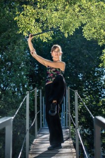 Woman practices tai chi sword on a bridge. The tai chi sword is an important instrument in this practice