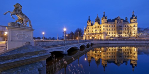 Illuminated Schwerin Castle with the castle bridge to the castle island in the evening