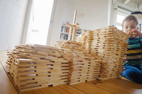 Symbolic photo on the subject of creative play among children. A boy builds with wooden building blocks. Berlin