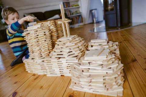Symbolic photo on the subject of creative play among children. A boy builds with wooden building blocks. Berlin