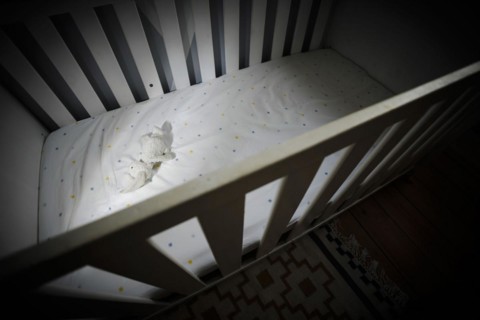 Symbolic photo on the subject of child abuse. A stuffed animal lies in an empty cot. Berlin