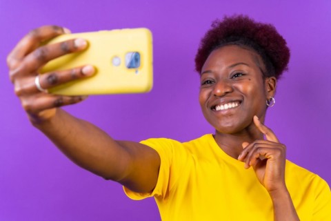 Young african american woman isolated on a purple background smiling and making a selfie