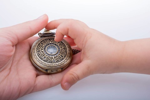 Retro style pocket watch in hand on white background