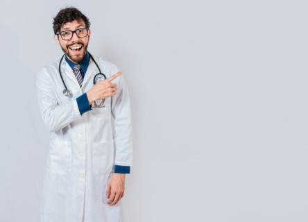 Young doctor pointing a promotion with finger. Happy doctor pointing at advertising space isolated. Happy doctor pointing right with finger