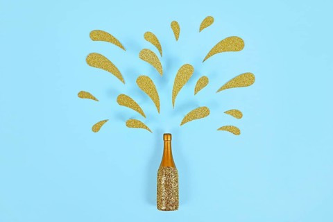 Golden splashing Champagne bottle on blue background