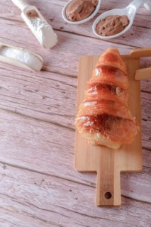 Puff pastry horn filled with pastry cream with some spoons with cocoa