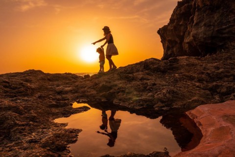 Silhouette of mother and son walking in the sunset on the beach of Tacoron in El Hierro